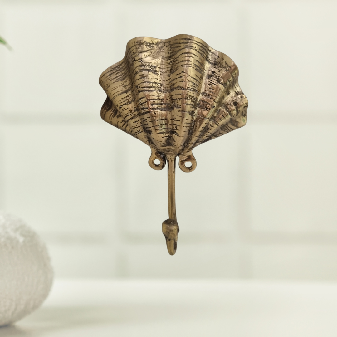 Brass clam shell wall hook mounted on white subway tiles in a coastal bathroom setting