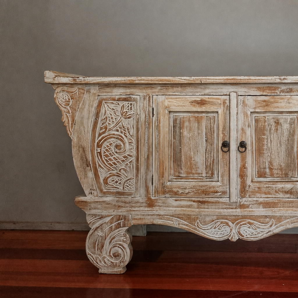 Close view of the floral carving, distressed finish and scroll-shaped leg.