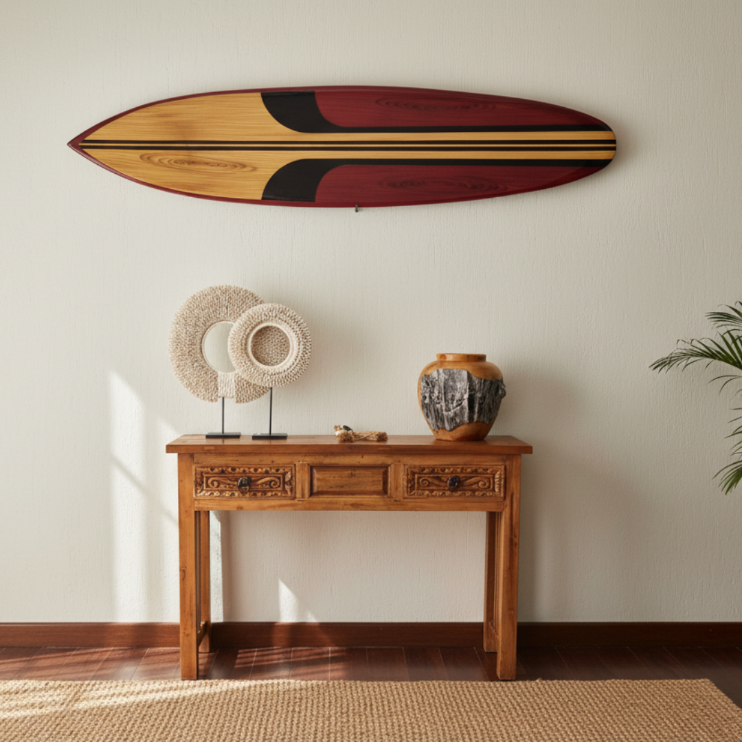 Decorative surfboard wall art mounted above a carved timber console table styled with coastal home décor accessories