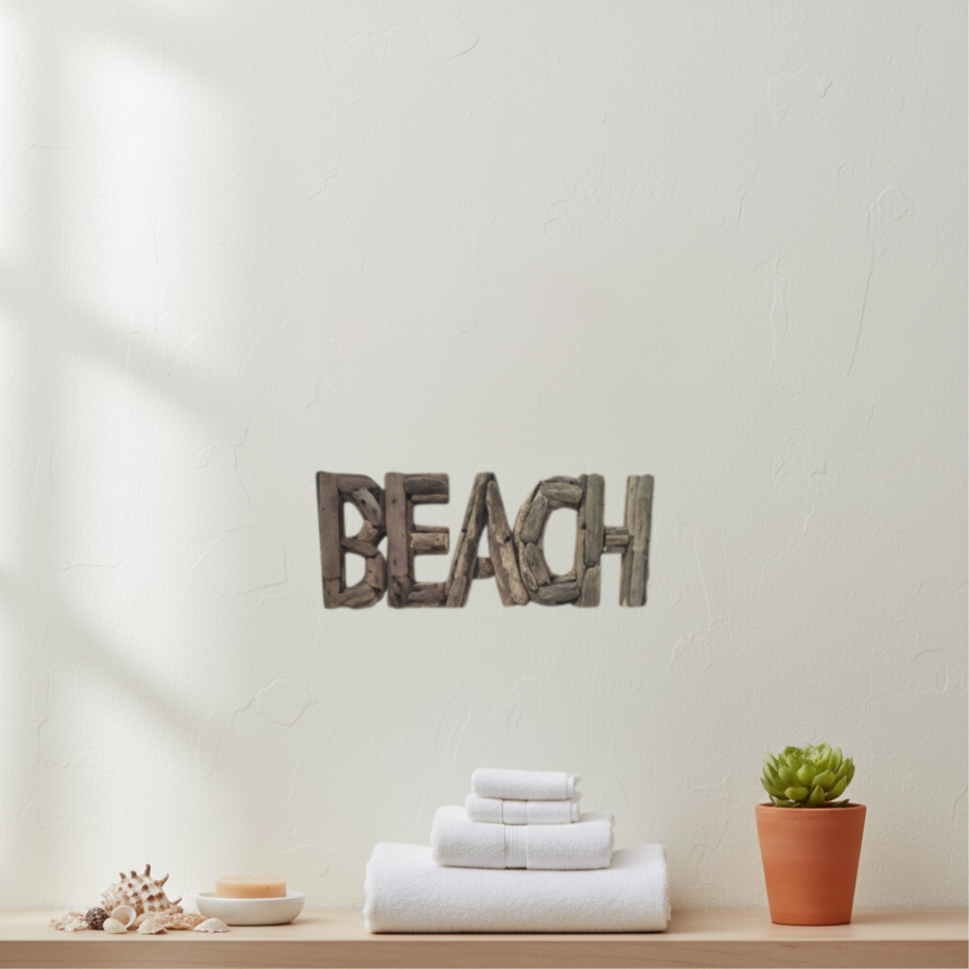 Rustic wooden wall decor spelling 'BEACH' mounted on a textured off-white wall above a light wood shelf with folded white towels, a small potted succulent, and seashells.