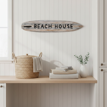 Grey-wash wooden wall decoration mounted above a pale timber laundry bench in a bright white coastal laundry