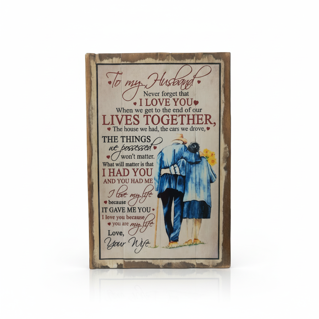 A rectangular wooden plaque with a distressed brown border, featuring a romantic message addressed to a husband and an illustration of a couple in blue clothing, shown on a white background with a soft reflection.