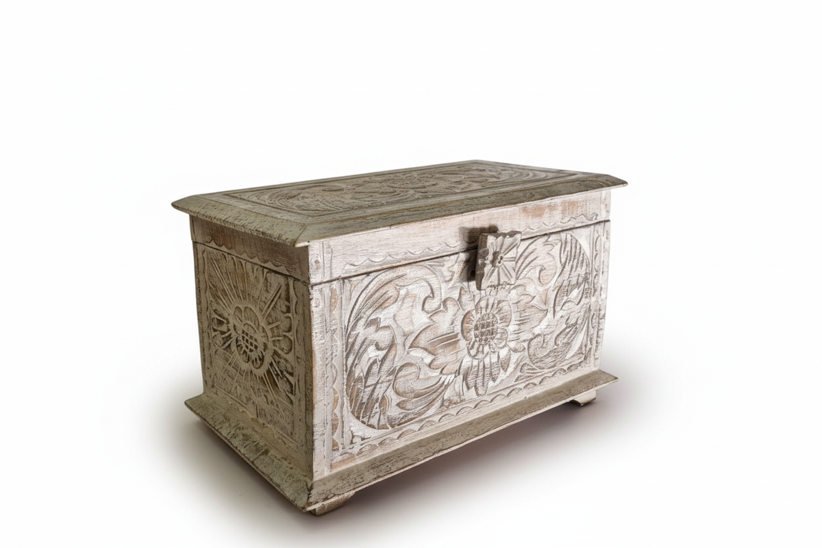A carved wooden storage chest with floral and sun motifs, featuring a weathered white and gray finish, photographed on a white background.