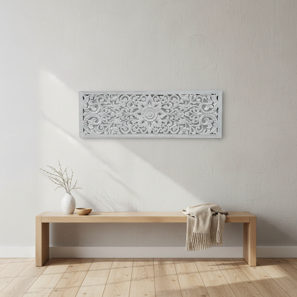White carved rectangular décor mounted above a short light-oak console against a cool white backdrop, styled with a ceramic vase and pale branches.