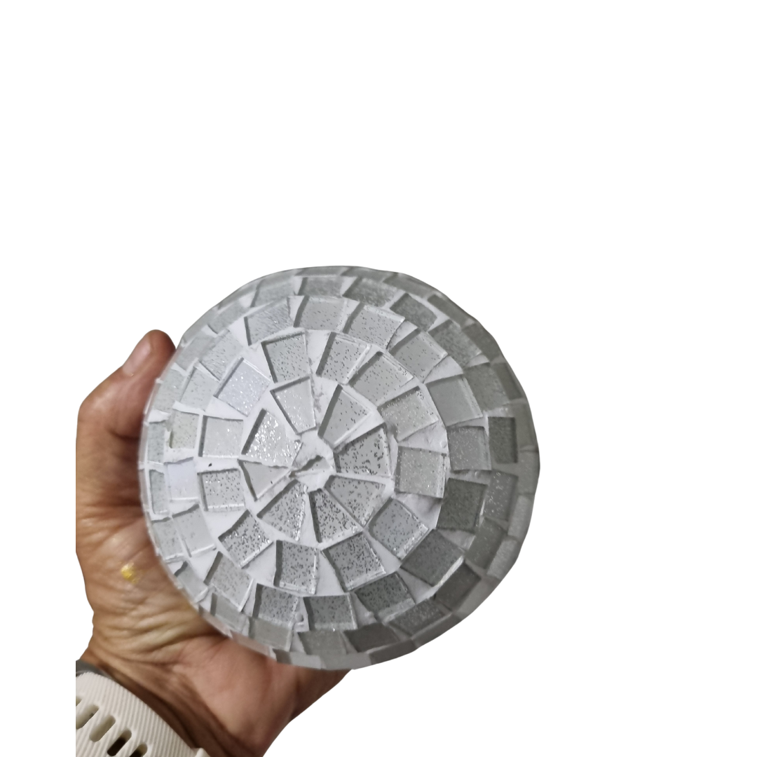 mosaic decorative ball in white, each with a geometric pattern made of small tiles in a hand to show the larger size of the range on a white wall 