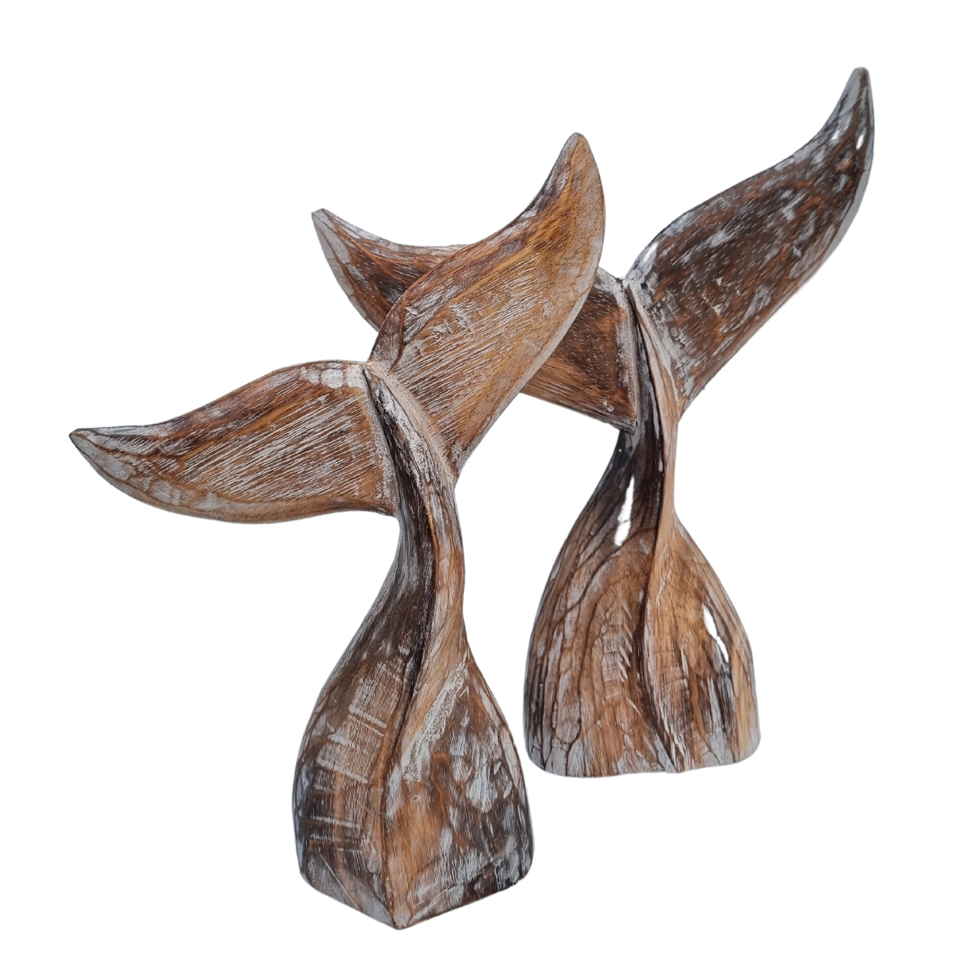 A handcrafted wooden carving of a whale tail with natural wood color 
