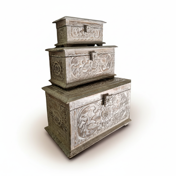 Three stacked Balinese-style carved wooden storage boxes with a distressed whitewash finish.