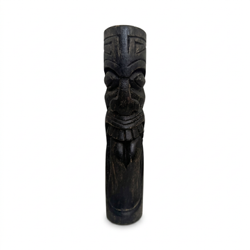 Dark timber carving with rounded eyes, a patterned forehead and a long tongue extending below its teeth, standing on a white background