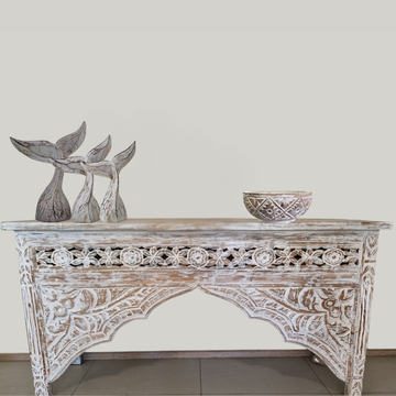 Decorative wooden console table with intricate carvings, featuring three whale tail sculptures and a bowl on a plain background.
