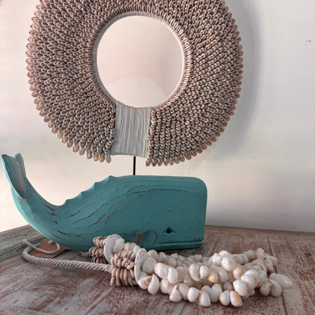wooden whale sculpture, and shell necklace on a wooden surface.