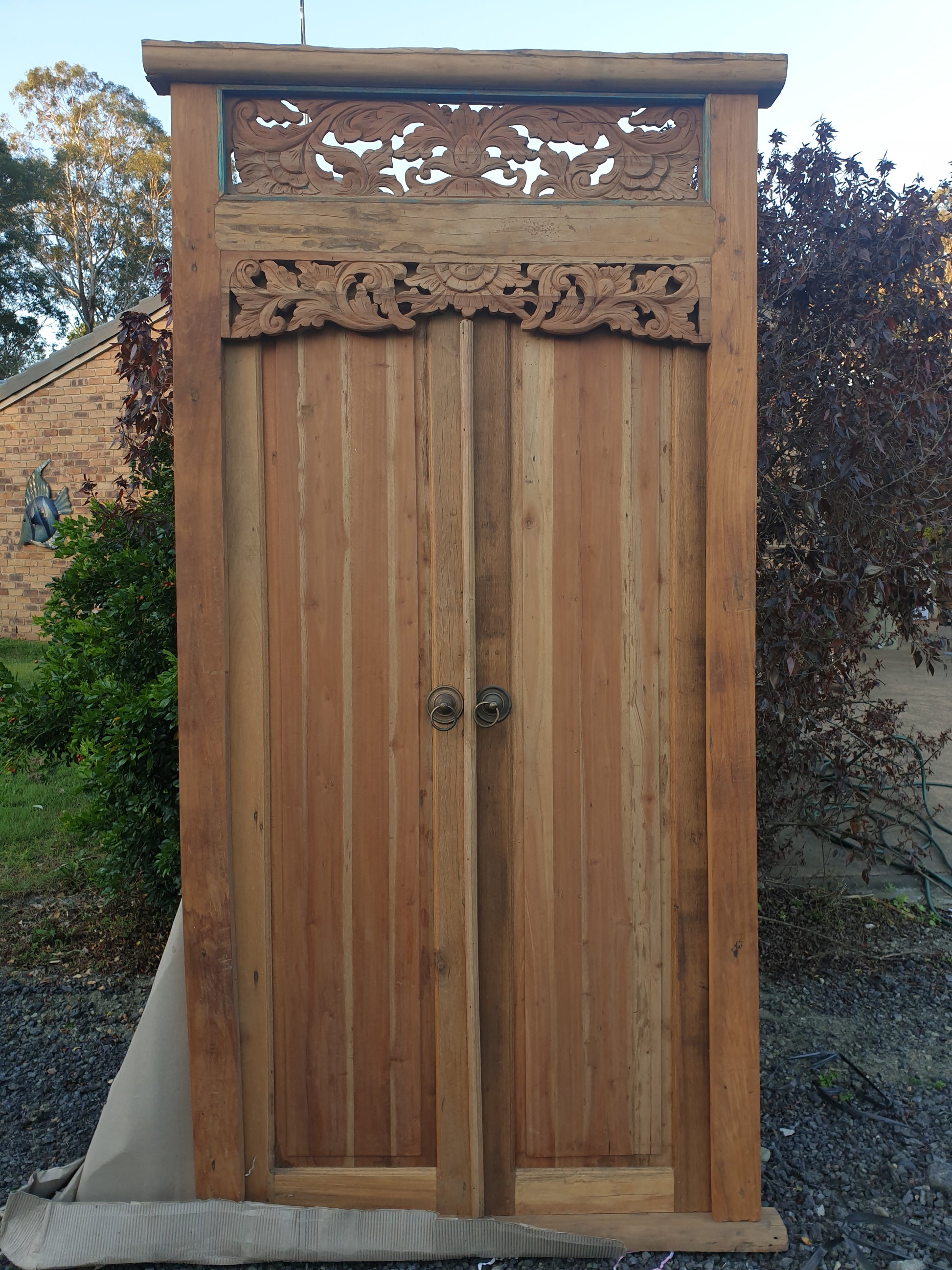 wooden door carved with Balinese artwork in a garden 