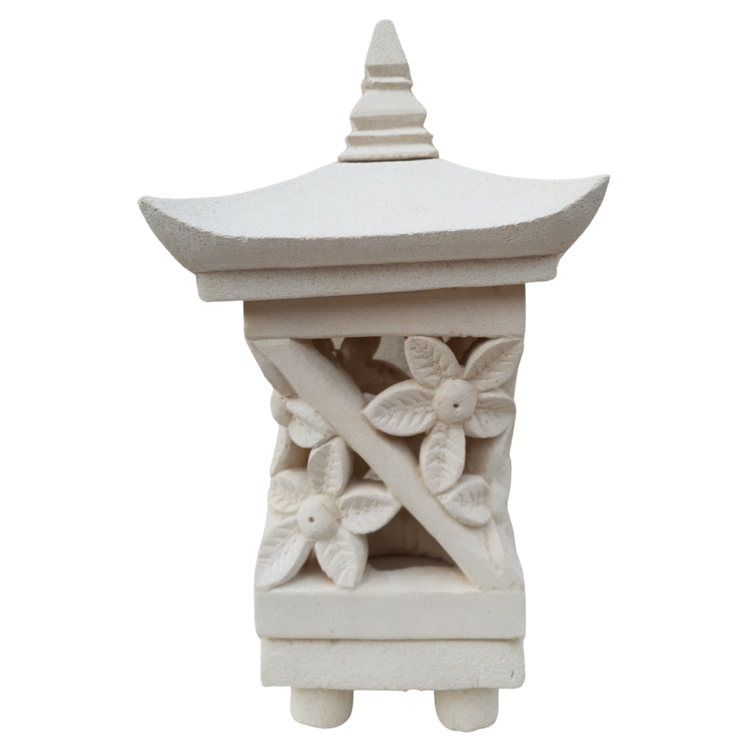 Artisan carved stone lantern with hibiscus motif on outdoor table